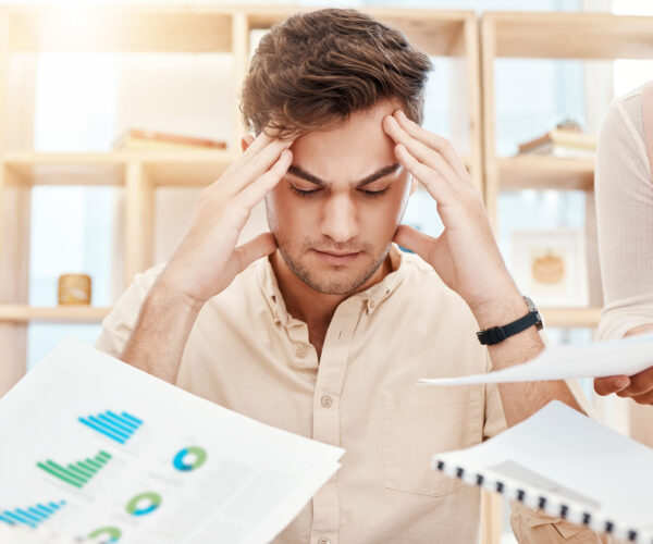 Stress, young man and headache being overworked, upset and tired in office. Business, employee and male experience burnout, frustrated and depressed with multiple task with anxiety and mental health.